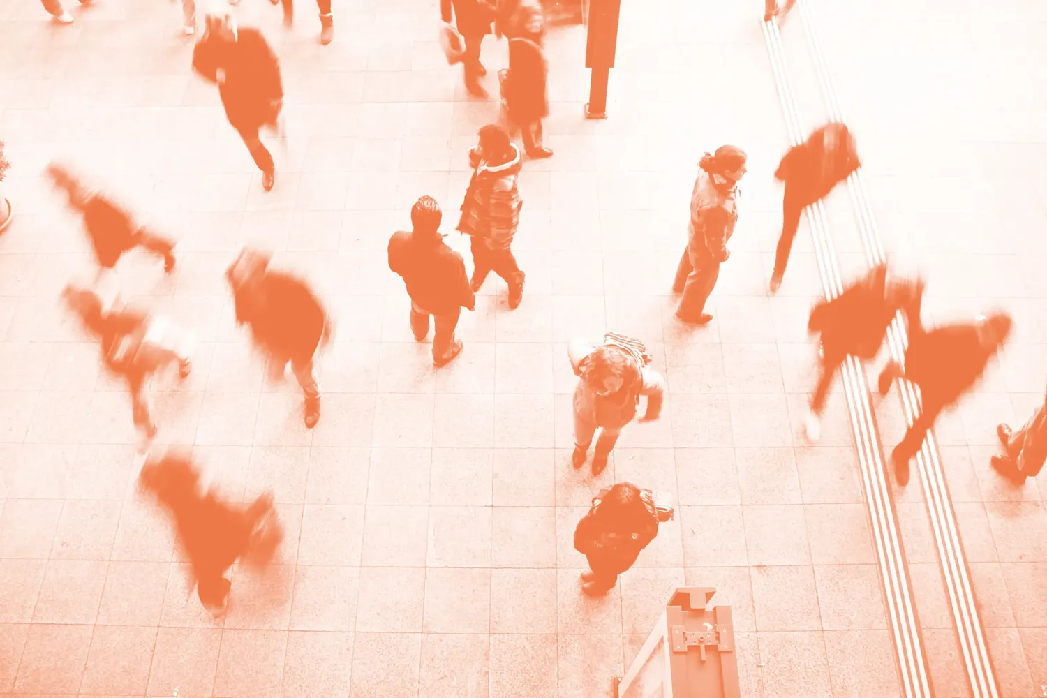 People crossing a public square, seen from above in warm orange tones